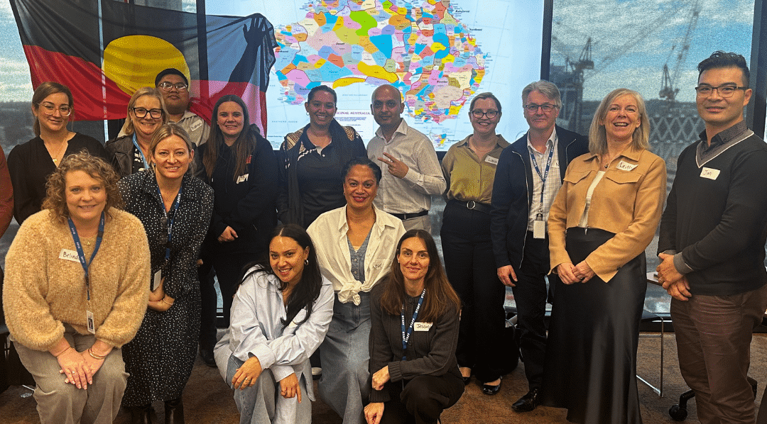 Afford leaders pose in front of the Indigenous flag and a map of Australia showing First Nations peoples geography.
