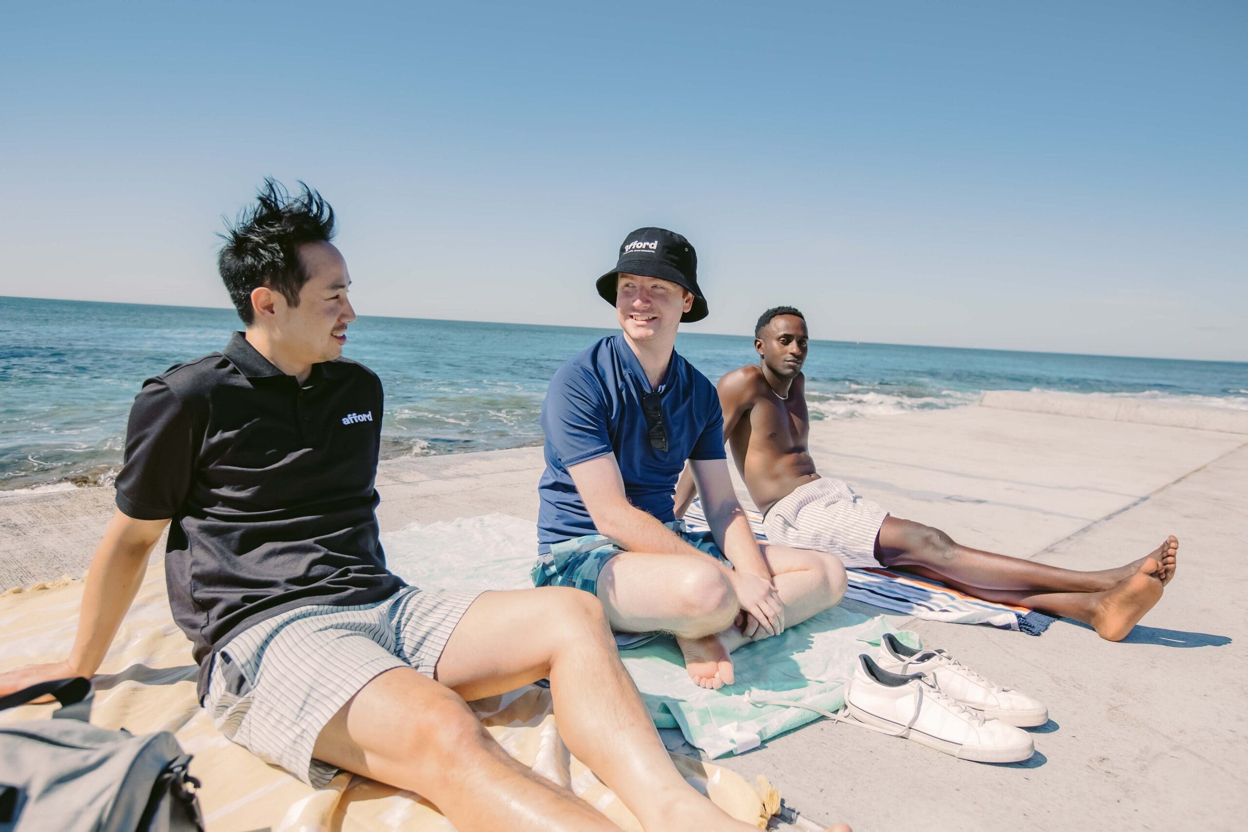 A support worker and two SIL clients sitting by the pools.