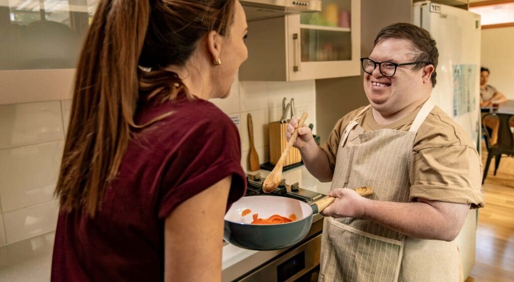 A support worker and a SIL client cooking up a meal together.